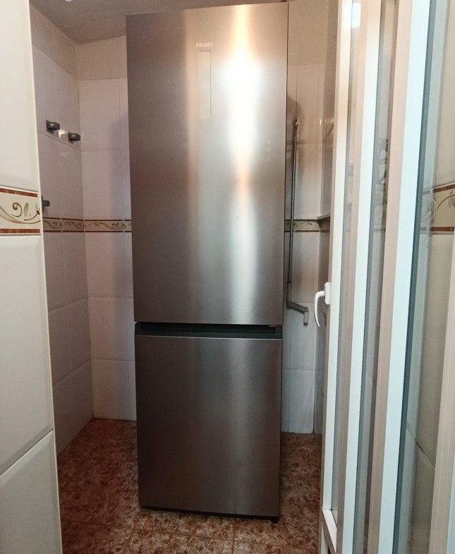 Haier kyl/frys i litet kaklat rum.
