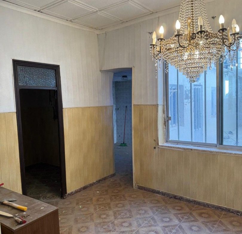 Gammalt rum med kristallkrona, kaklat golv, redo för renovering.