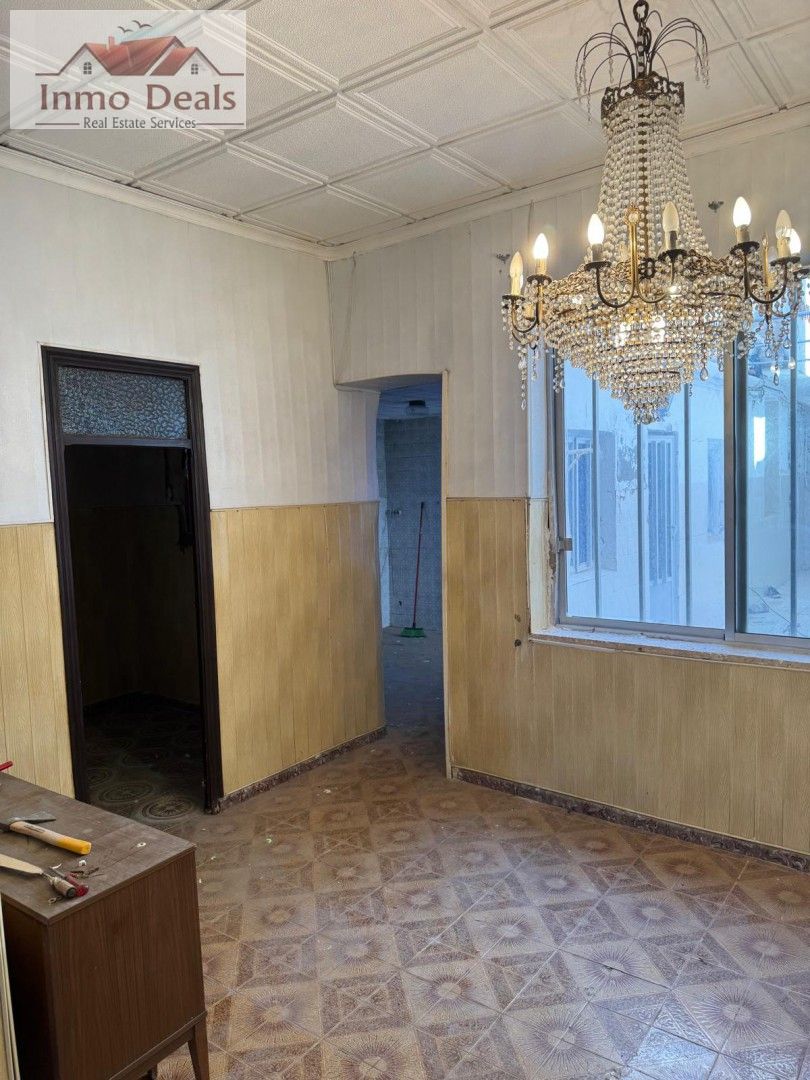 Gammalt rum med kristallkrona, kaklat golv, redo för renovering.