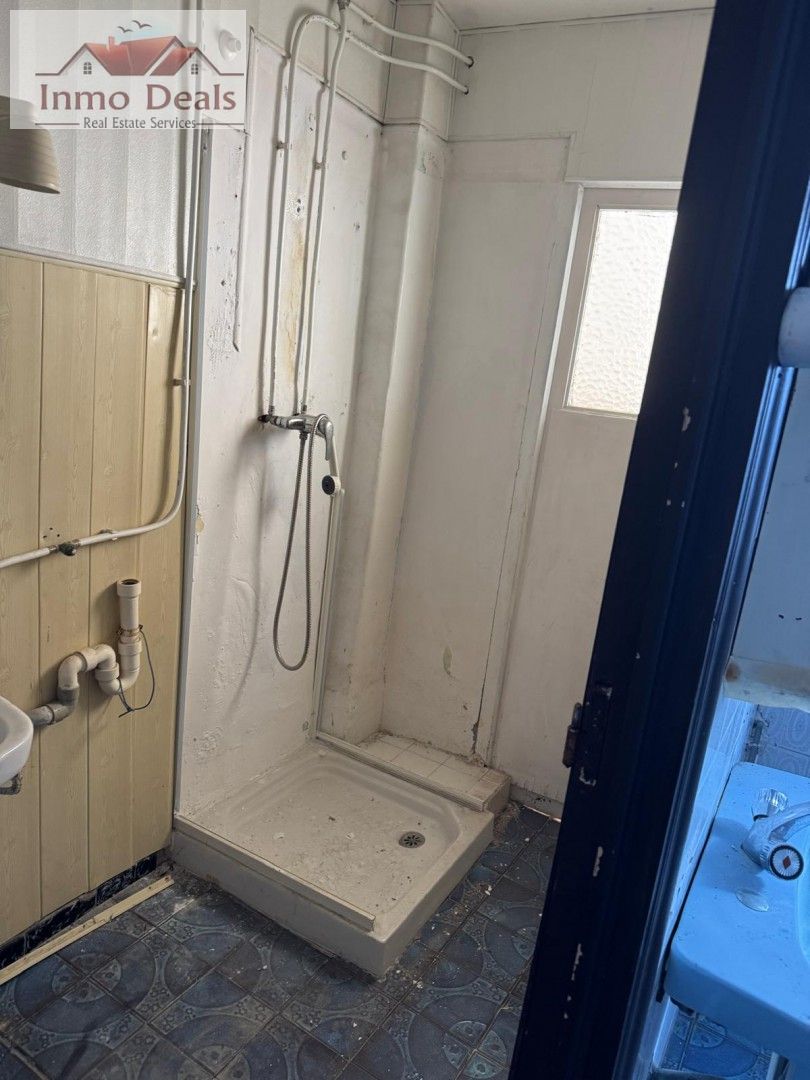 Gammalt, smutsigt badrum med dusch, stort renoveringsbehov.