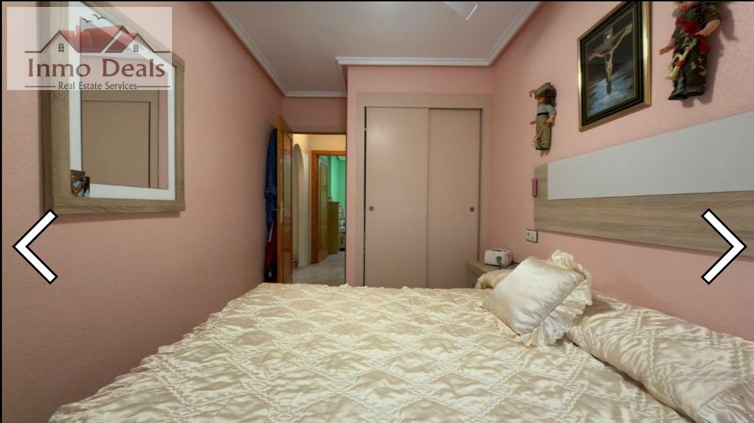 Sovrum med rosa väggar, säng, garderob och spegel.