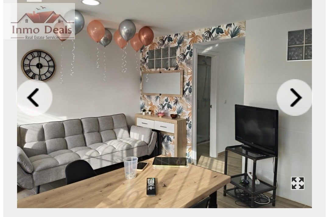 Vardagsrum med soffa, bord, TV och ballonger.