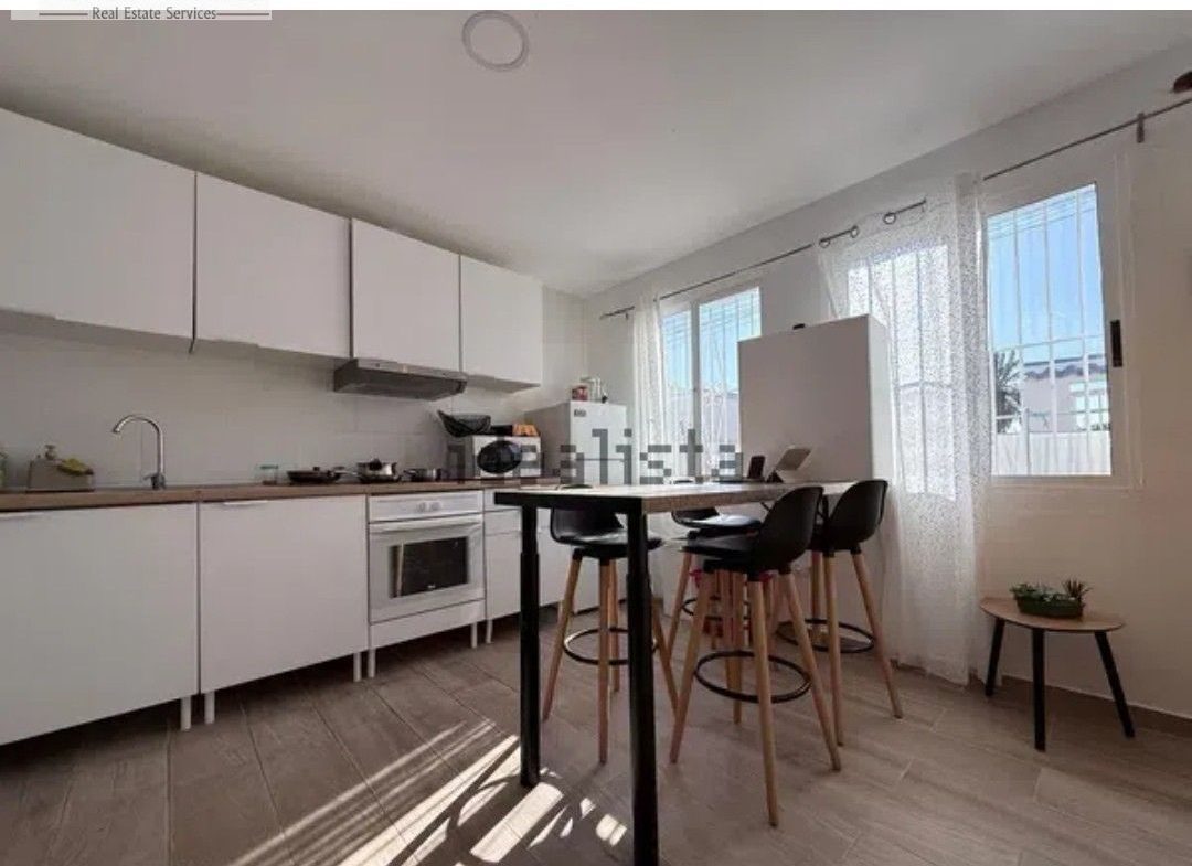 Modernt kök med frukostbar, vita skåp och dagsljus.
