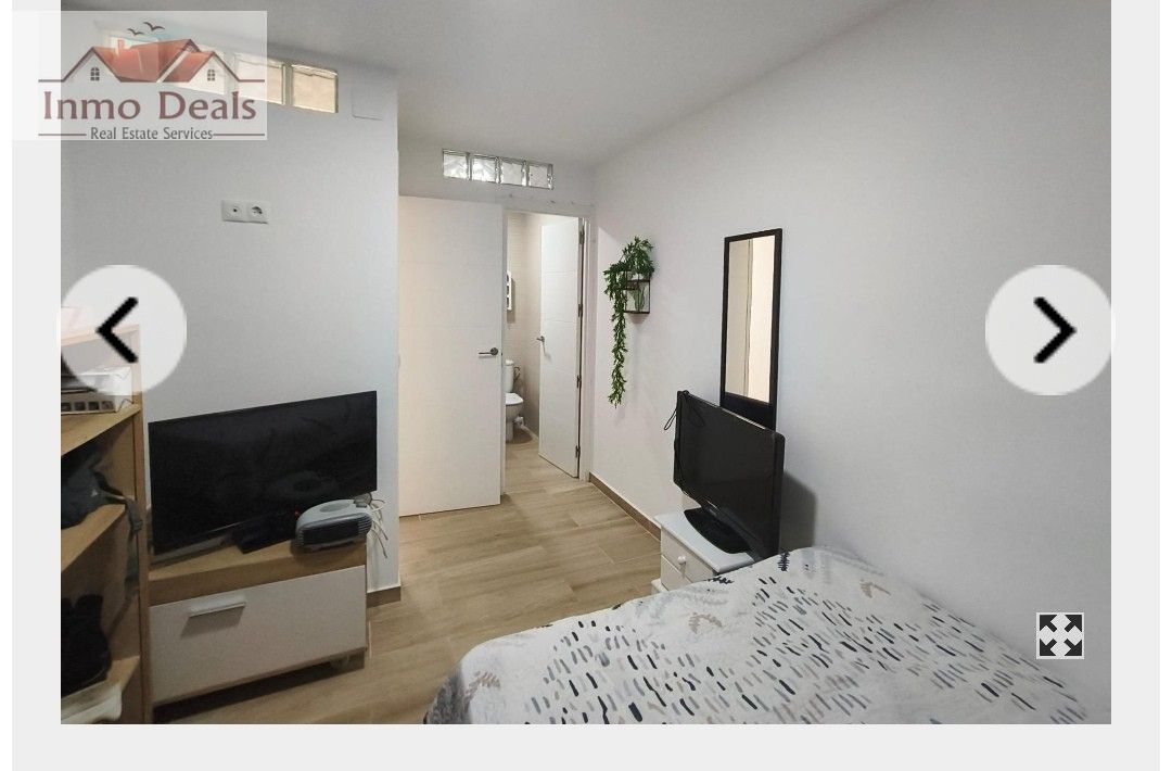 Modernt sovrum med säng, TV och anslutande badrum.
