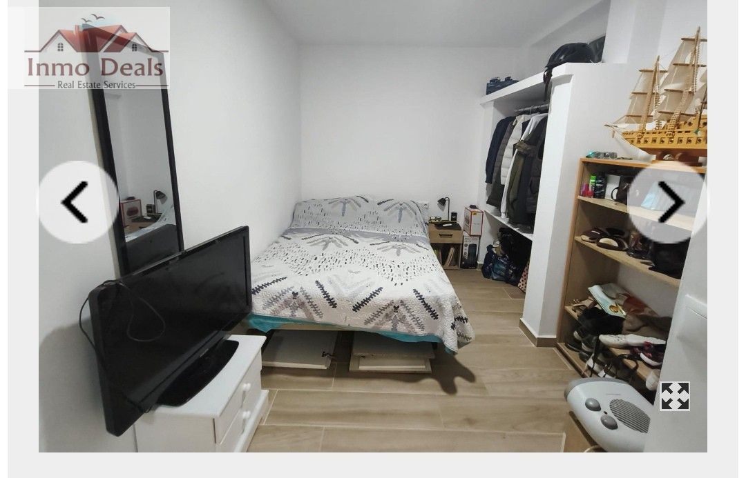 Mysigt sovrum med säng, TV, spegel och öppen garderob.
