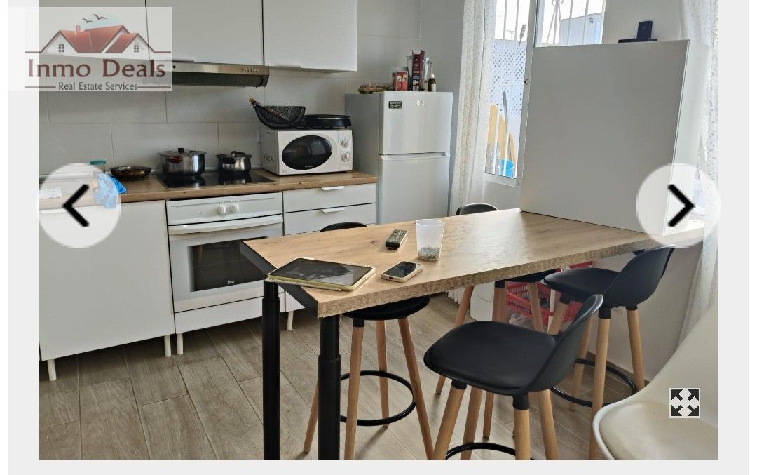 Ljust, modernt kök med matplats och barstolar.