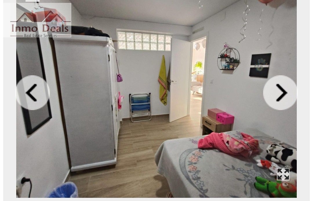 Ljust sovrum med säng, garderob och glasblocksfönster.