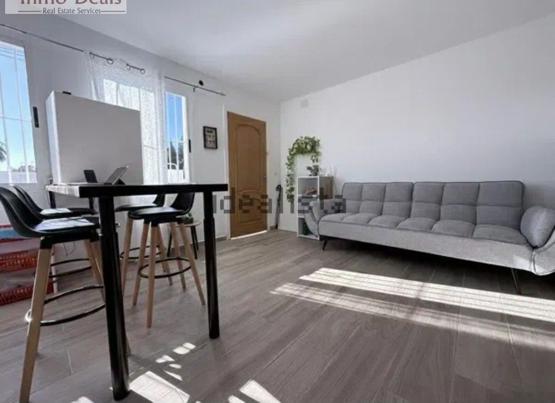 Ljust vardagsrum med grå soffa och barbord.