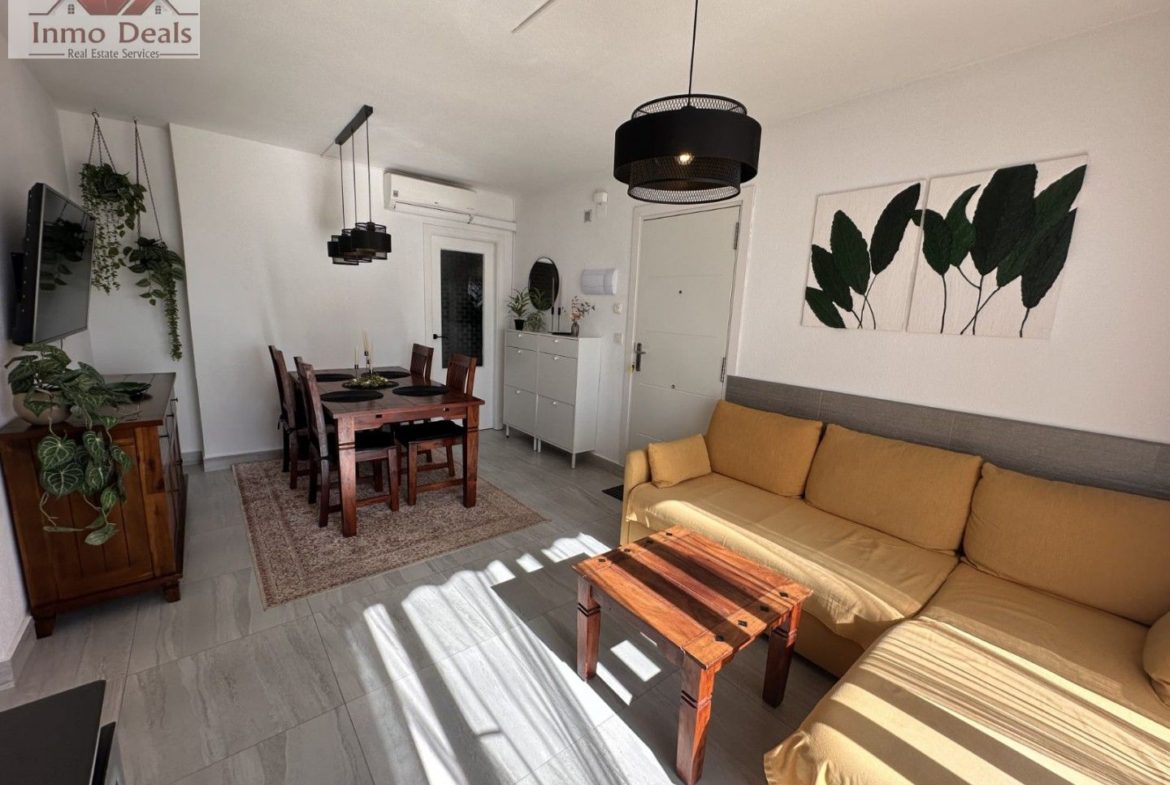 Ljust vardagsrum med matplats, gul soffa och solljus.