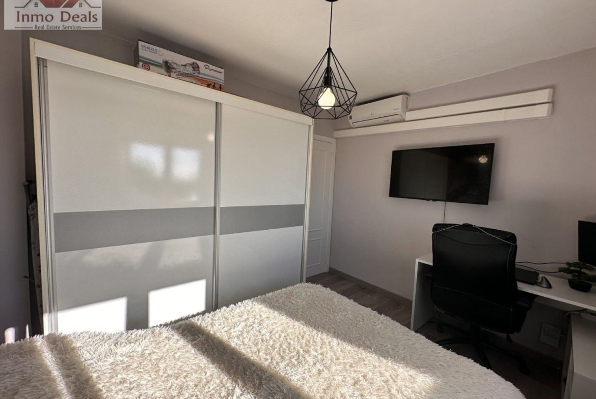 Modernt sovrum med garderob, säng, TV och skrivbord.