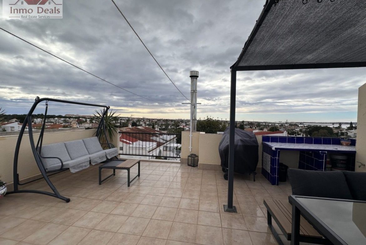 Rymlig takterrass med sittgrupp, grill och utsikt över stad och vatten.