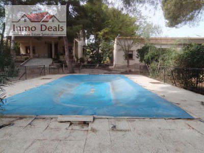 Villa med övertäckt pool och grön omgivning